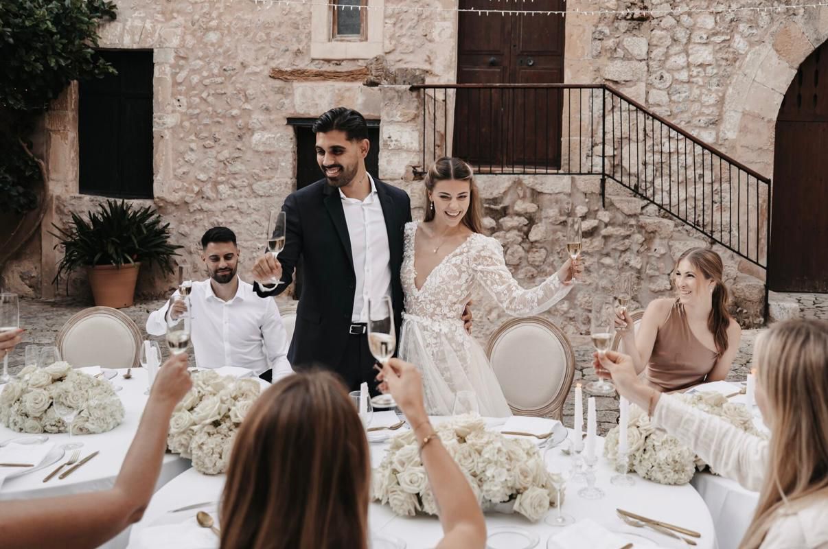 Brautpaar stößt mit Gästen an der Hochzeitstafel an
