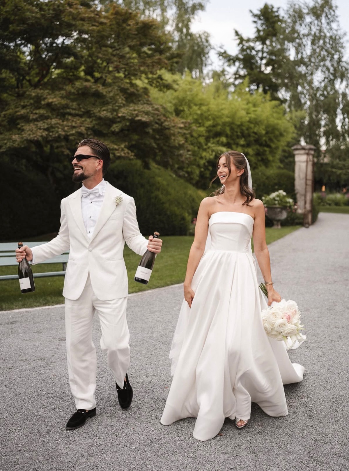 Brautpaar mit Champagnerflaschen im Park